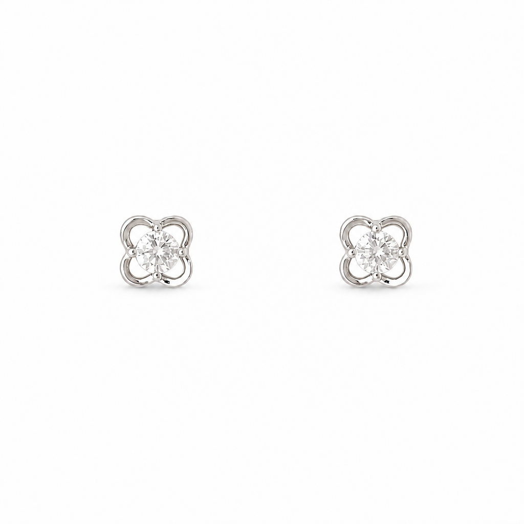 A pair of silver-toned four-leaf clover stud earrings with clear round-cut center stones, set against a plain white background.